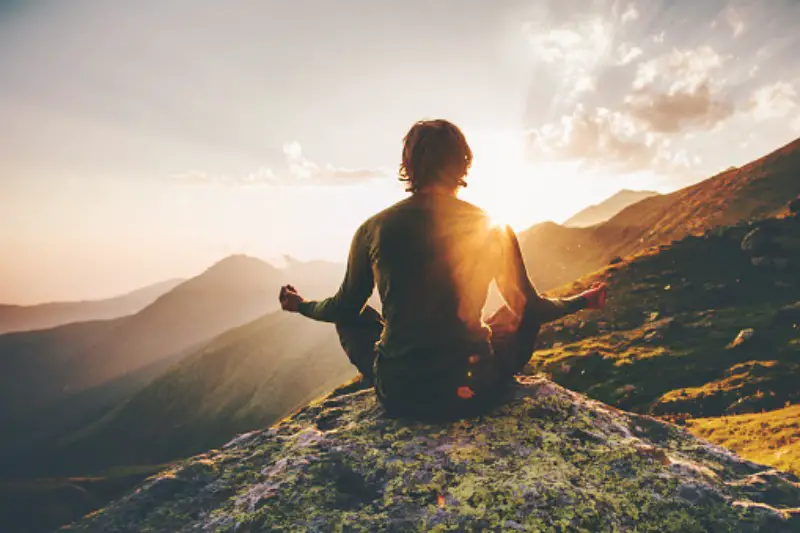 man meditating on a mountain