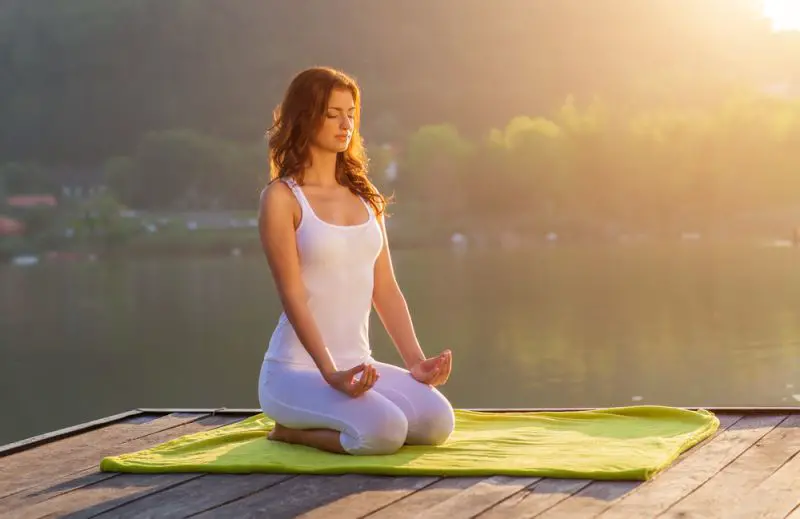 Woman Yoga - relax on the pier at the lake