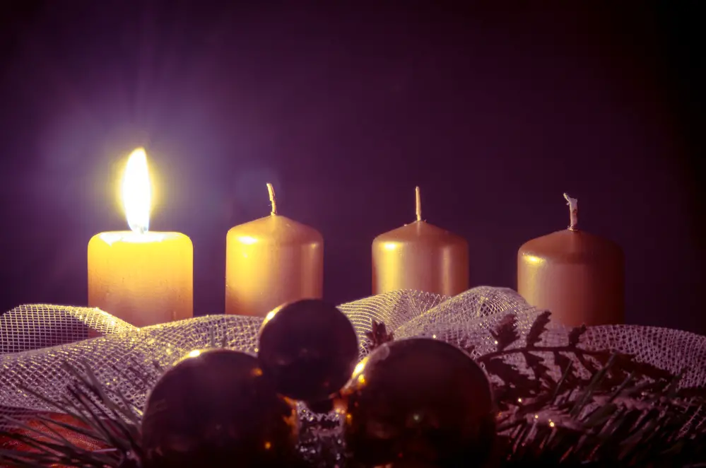 advent wreath with one burning candle against purple background
