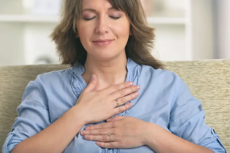 Woman practicing self Reiki transfering energy through palms, a kind of energy medicine.