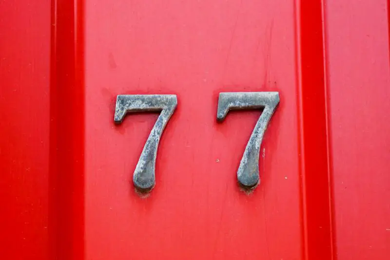 house number 77 on iron red background, seventy-seven.