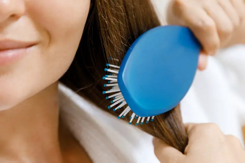 Woman is combing her hair at home